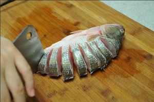 將鱸魚清洗干凈，從脊椎處切斷至腹部，腹部保留1cm左右不要切斷。