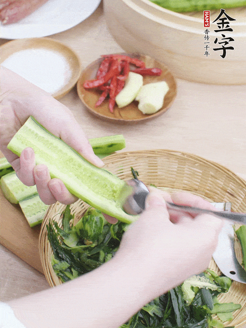 黃瓜削皮，對半切開，勺子挖去內(nèi)瓤，斜刀切片。青蒜斜刀切段。